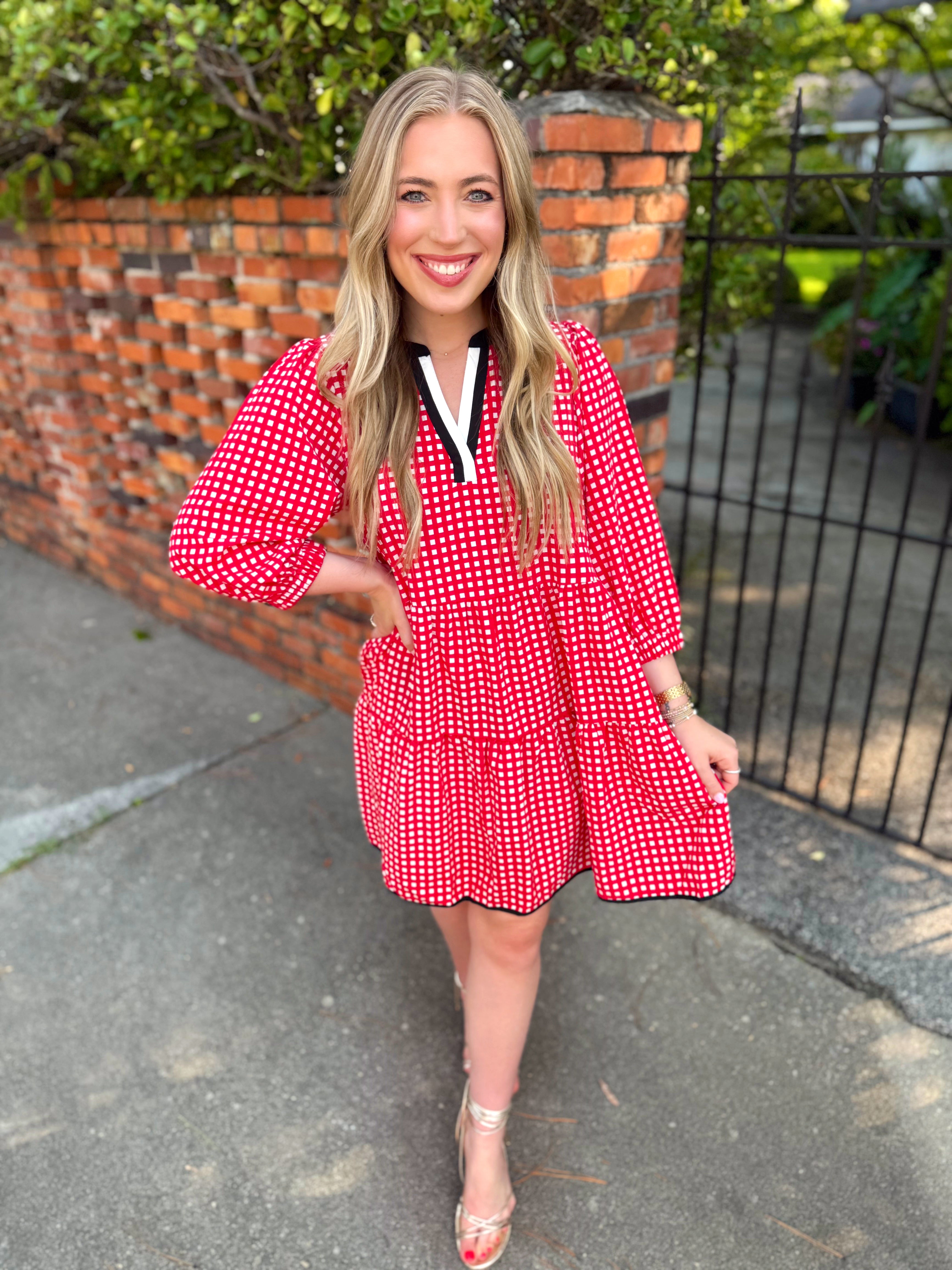 A red and white gingham tiered mini dress with a black and white V-neckline by Mary Square