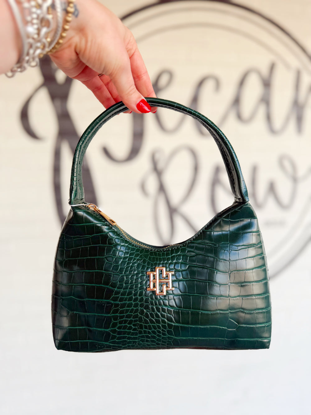 This deep forest green handbag features a luxe croc-embossed finish, structured silhouette, and sleek top handle.