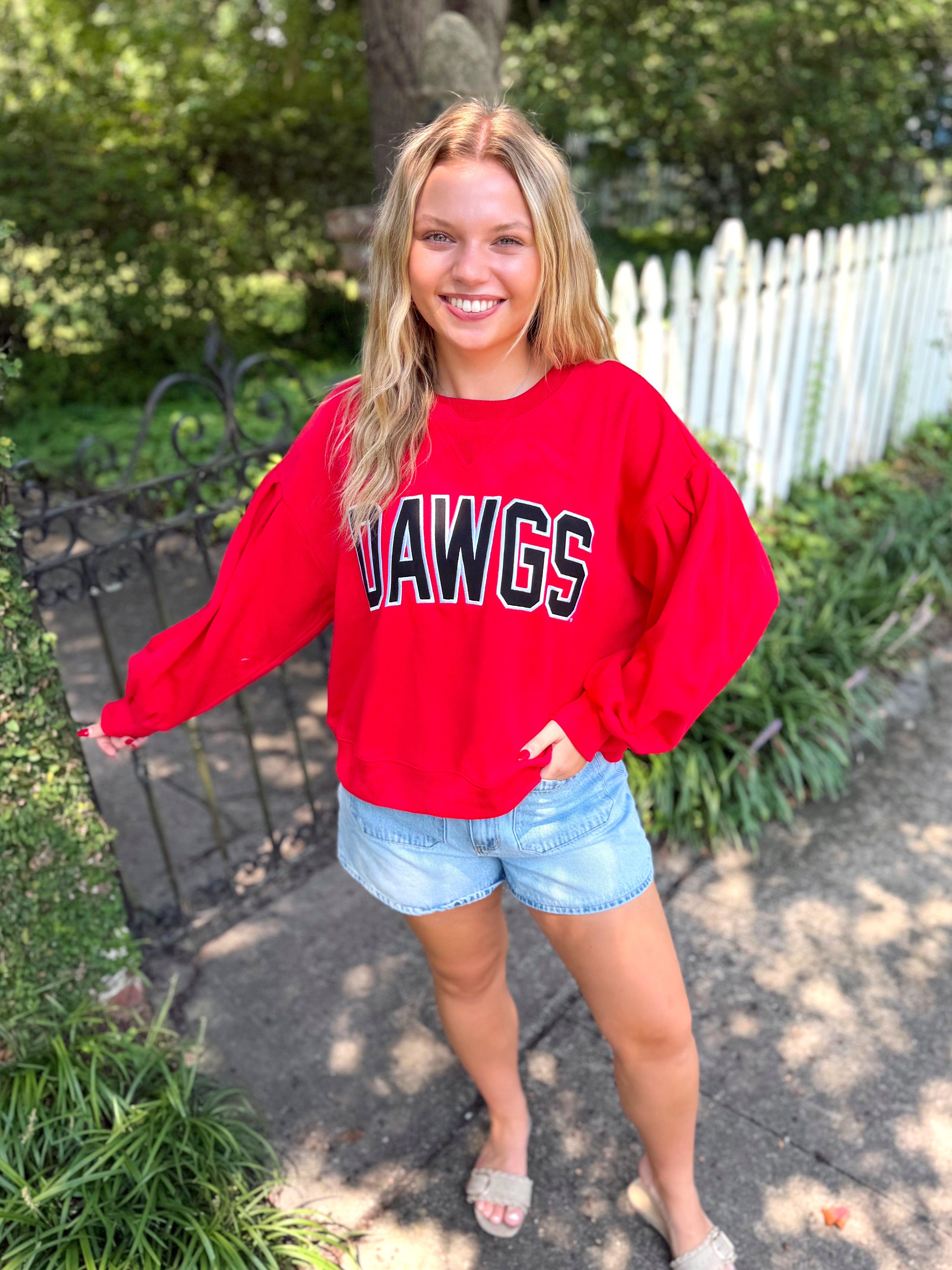 A red crewneck sweatshirt with 'DAWGS' printed across the chest in black and white lettering.  
