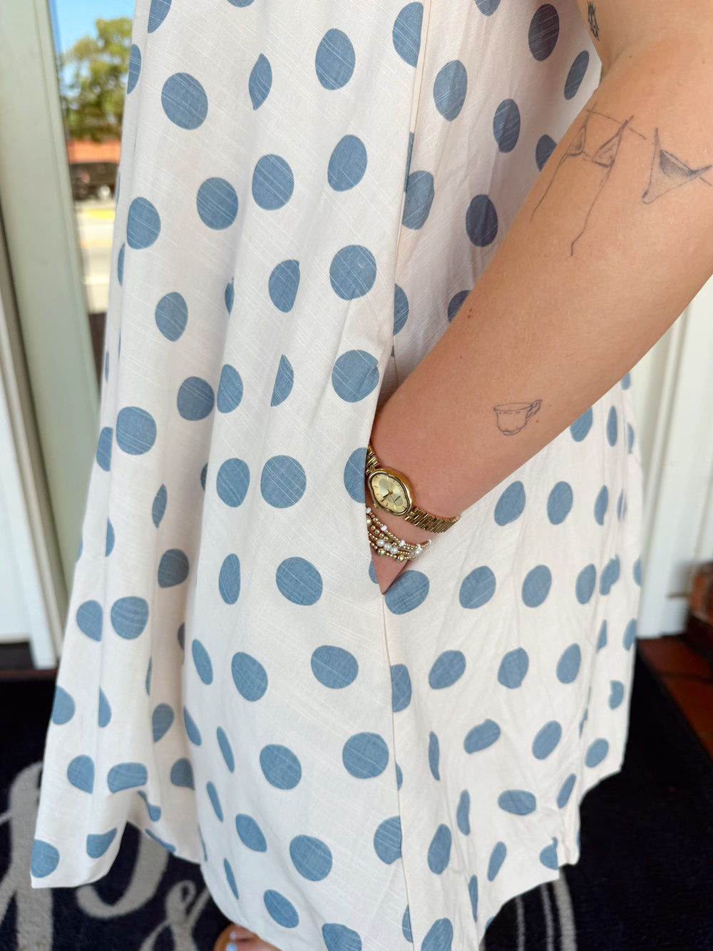 Cream swing mini dress with blue polka dots and adjustable tie shoulder straps.
