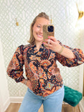 This paisley-inspired blouse features a gorgeous mix of warm rust, coral, teal, and neutral tones against a dark background. 