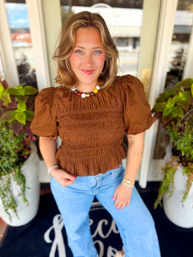  This rich brown top features a dainty black polka dot print with smocked detailing for added texture and a flattering, feminine shape. 