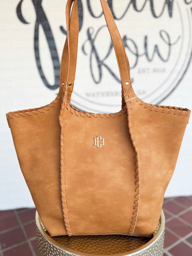  This warm camel tote features a soft, roomy silhouette with beautiful whipstitch detailing along the edges and handles. 