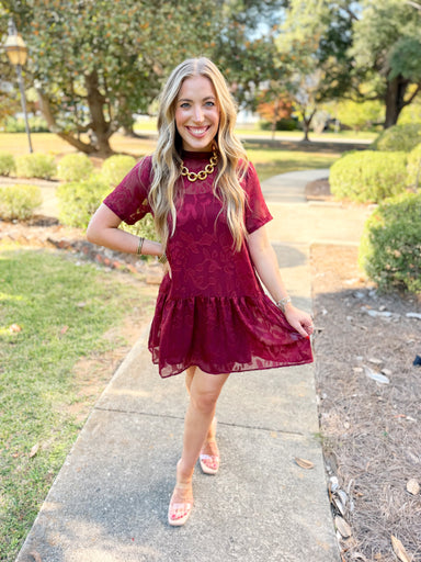 This floral jacquard mini dress features a textured finish, mock neckline, and short sleeves with an easy relaxed silhouette