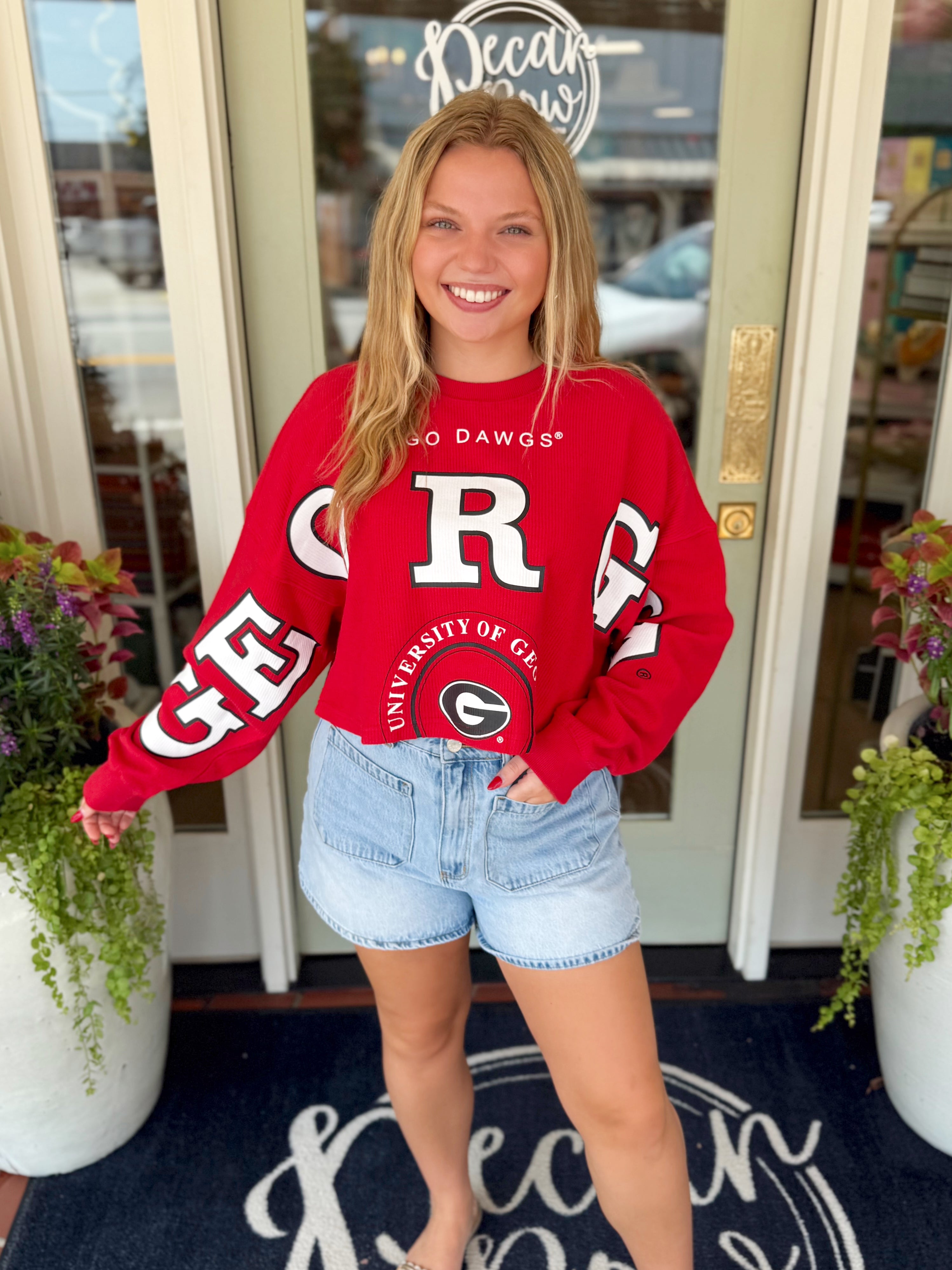 A red long-sleeve sweatshirt with large white 'Georgia' lettering and a University of Georgia logo.