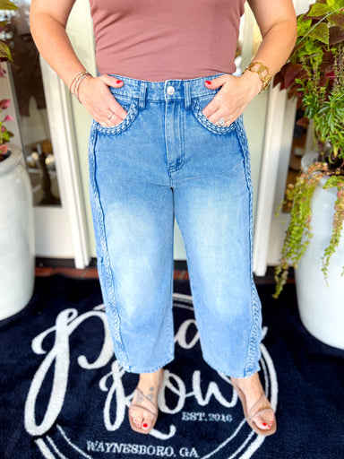 These cropped barrel jeans feature a relaxed, slightly curved-leg silhouette with statement braided trim along the sides and front pockets