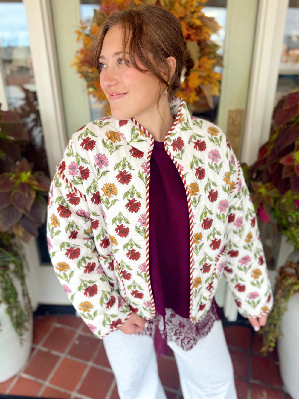 A charming quilted jacket featuring a colorful floral print, contrast striped trim, and an easy open-front fit.