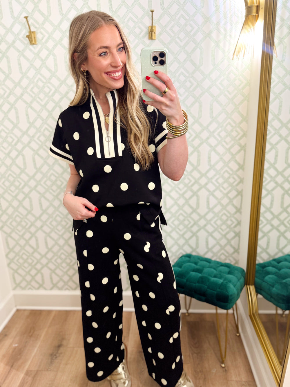 This polka dot top features a relaxed silhouette with a statement striped neckline, half-zip front, and matching striped trim at the sleeves