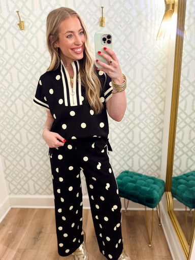 This polka dot top features a relaxed silhouette with a statement striped neckline, half-zip front, and matching striped trim at the sleeves