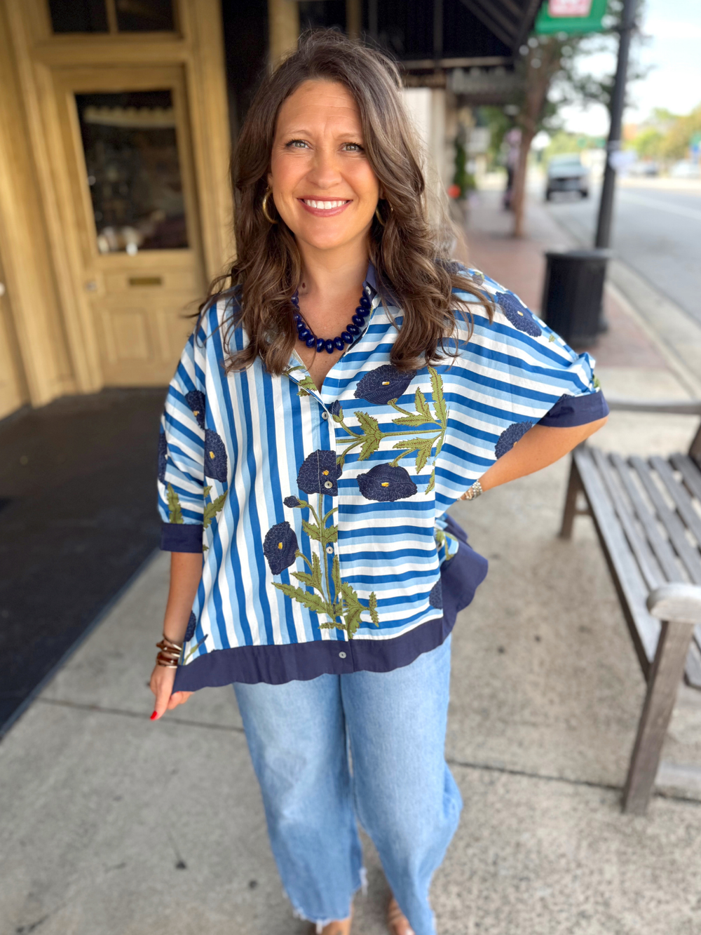 Blue and white striped short-sleeve floral blouse with a navy hem.