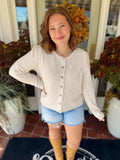 This soft cream cardigan features a simple round neckline, subtle gathered shoulders, and tonal textured buttons down the front.
