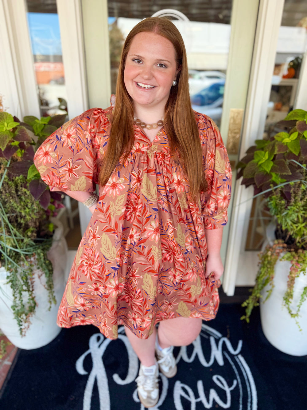 This babydoll mini dress features an oversized botanical print with voluminous puff sleeves and elastic cuffs.