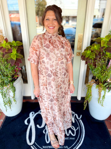This flowy dress features a latte background with a soft brown floral print, an elegant mock neckline, short flutter sleeves, and a relaxed silhouette.