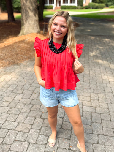 A red ruffled short-sleeve top with pleats down the front