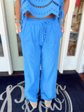 Bright blue wide-leg drawstring pants with eyelet detailing near the hem and relaxed flowy fit.