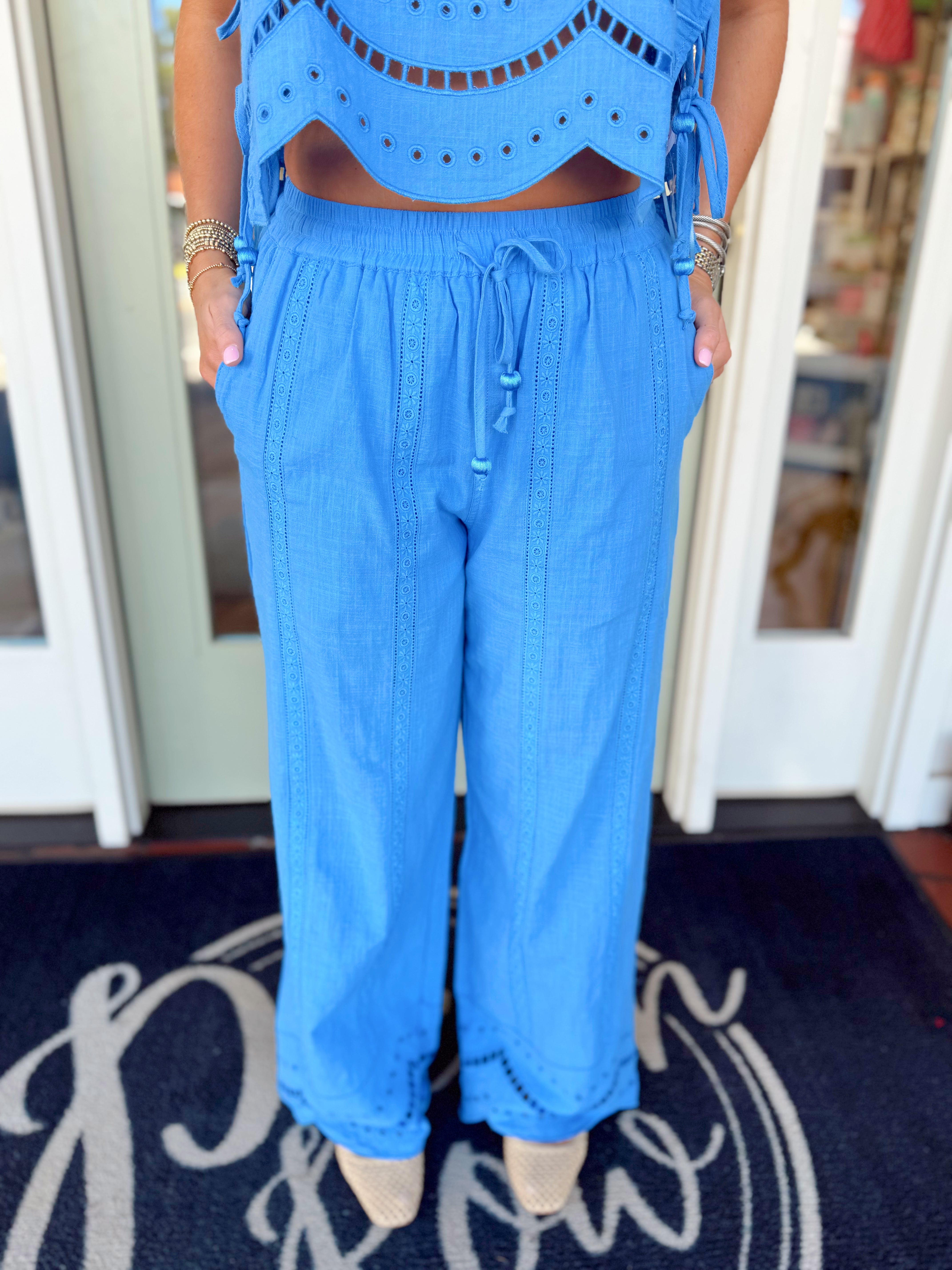 Bright blue wide-leg drawstring pants with eyelet detailing near the hem and relaxed flowy fit.