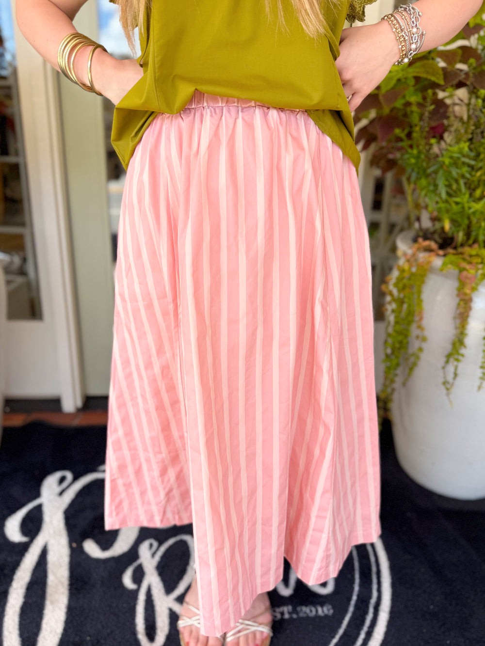 A classic striped midi skirt featuring soft blush and pink tones, an easy elastic waistband, and a full, flowy silhouette