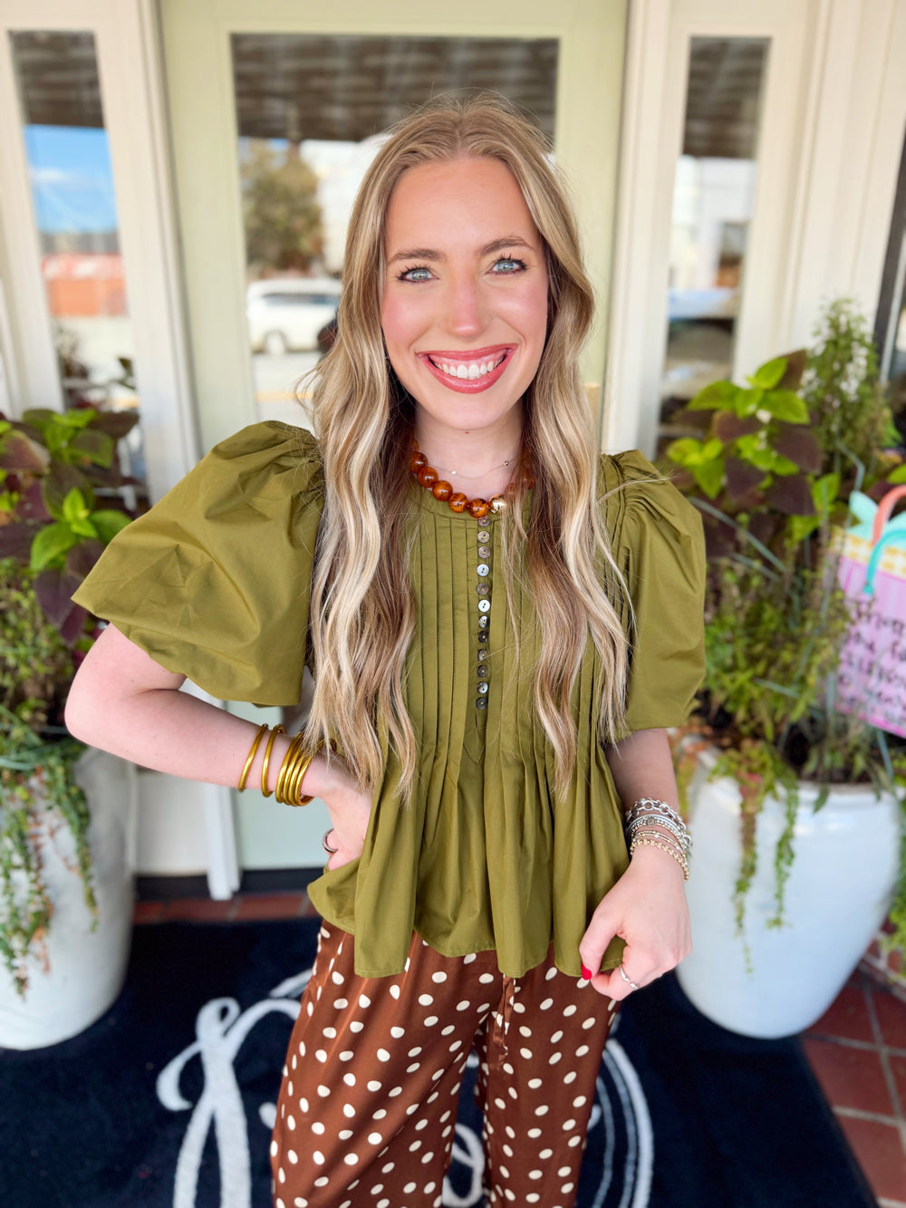 This solid short sleeve top features softly puffed sleeves, a classic round neckline, and a partial button front.