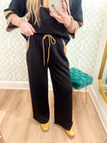 These pants feature a classic black body with warm camel contrast accents along the sides and pockets, plus a coordinating camel drawstring at the waist.