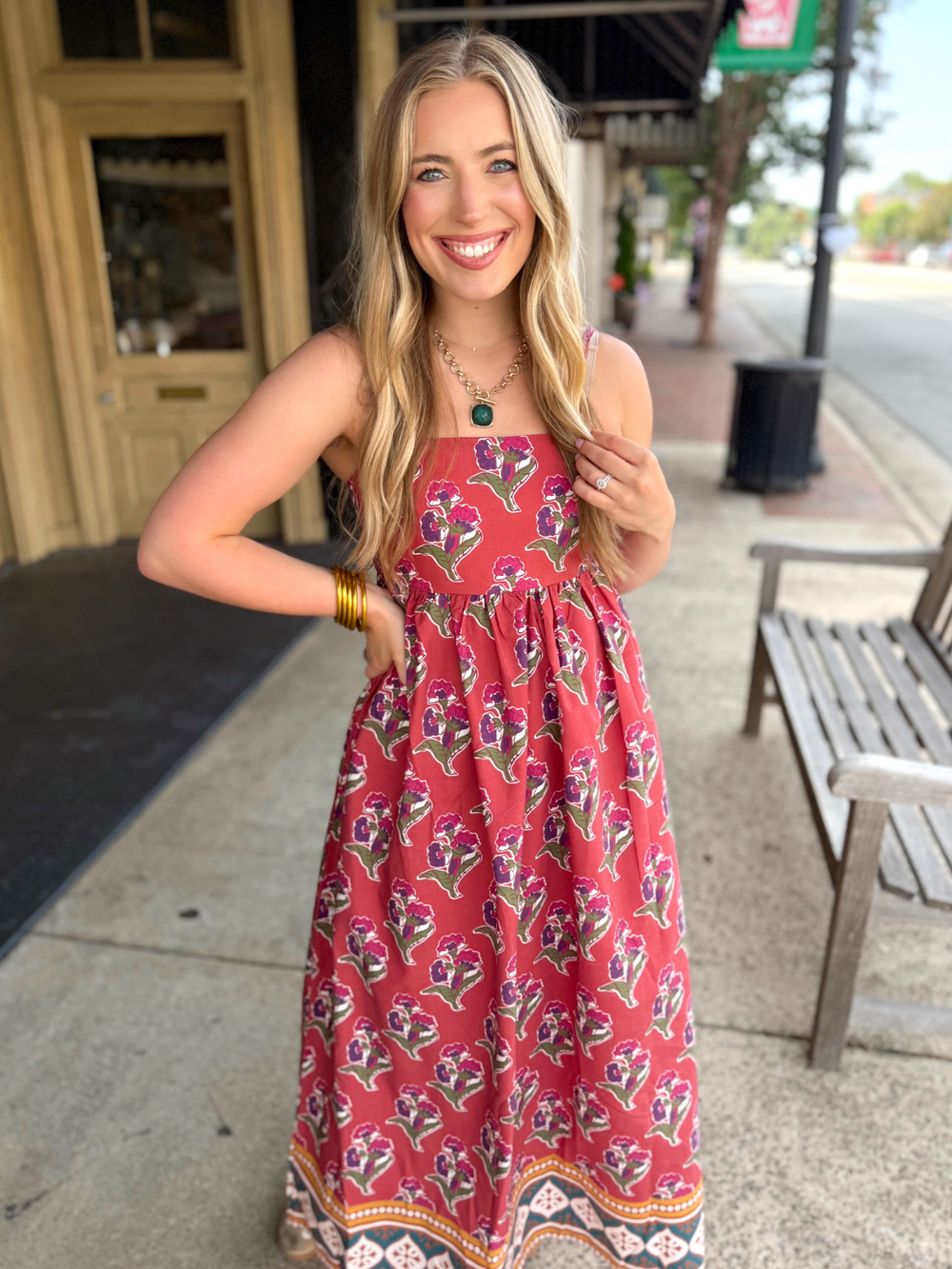 Sleeveless red maxi dress with a purple and green floral block print pattern. 