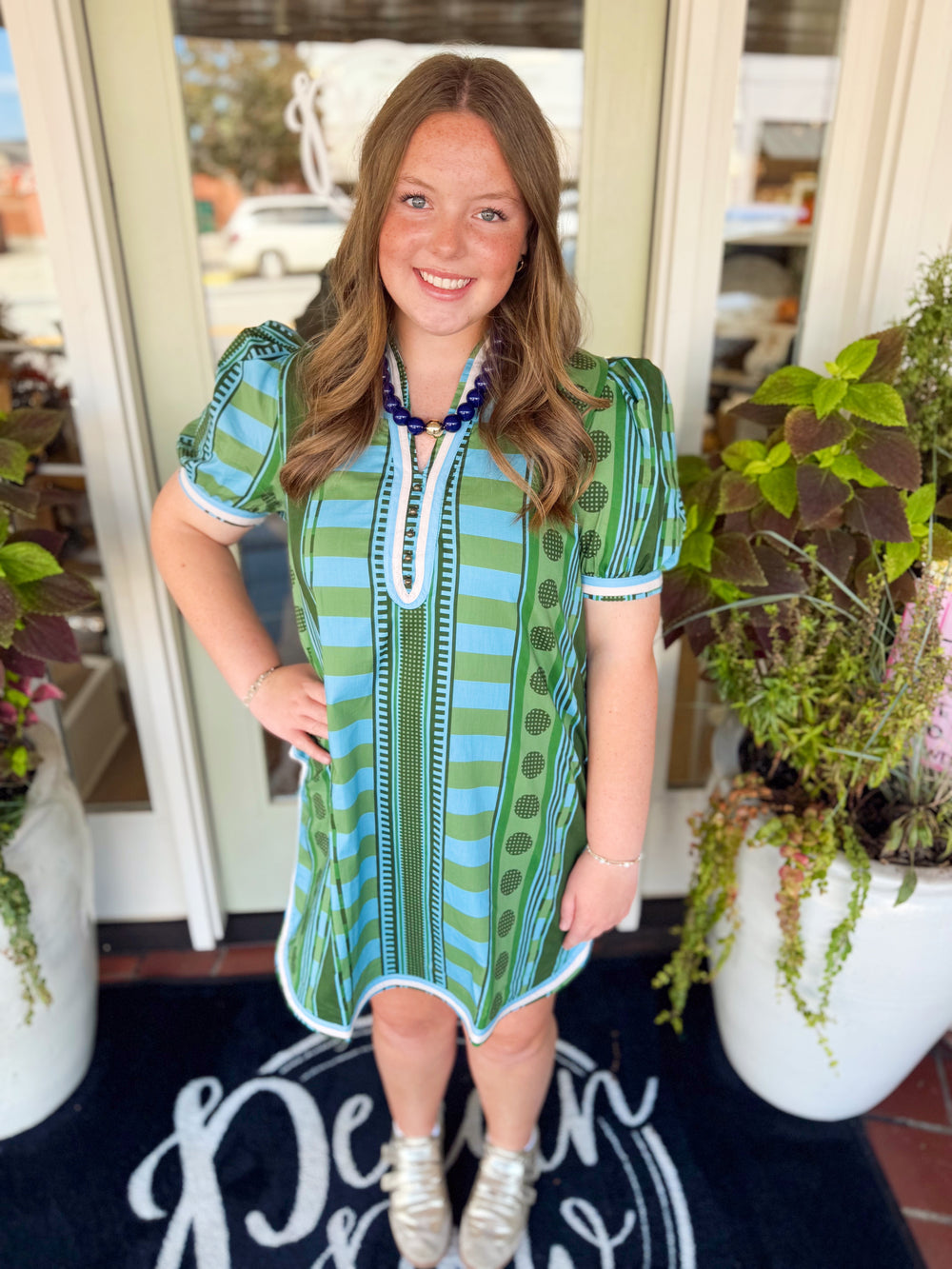  This printed mini dress features short puff sleeves, a flattering V-neckline, and button detailing down the front. 