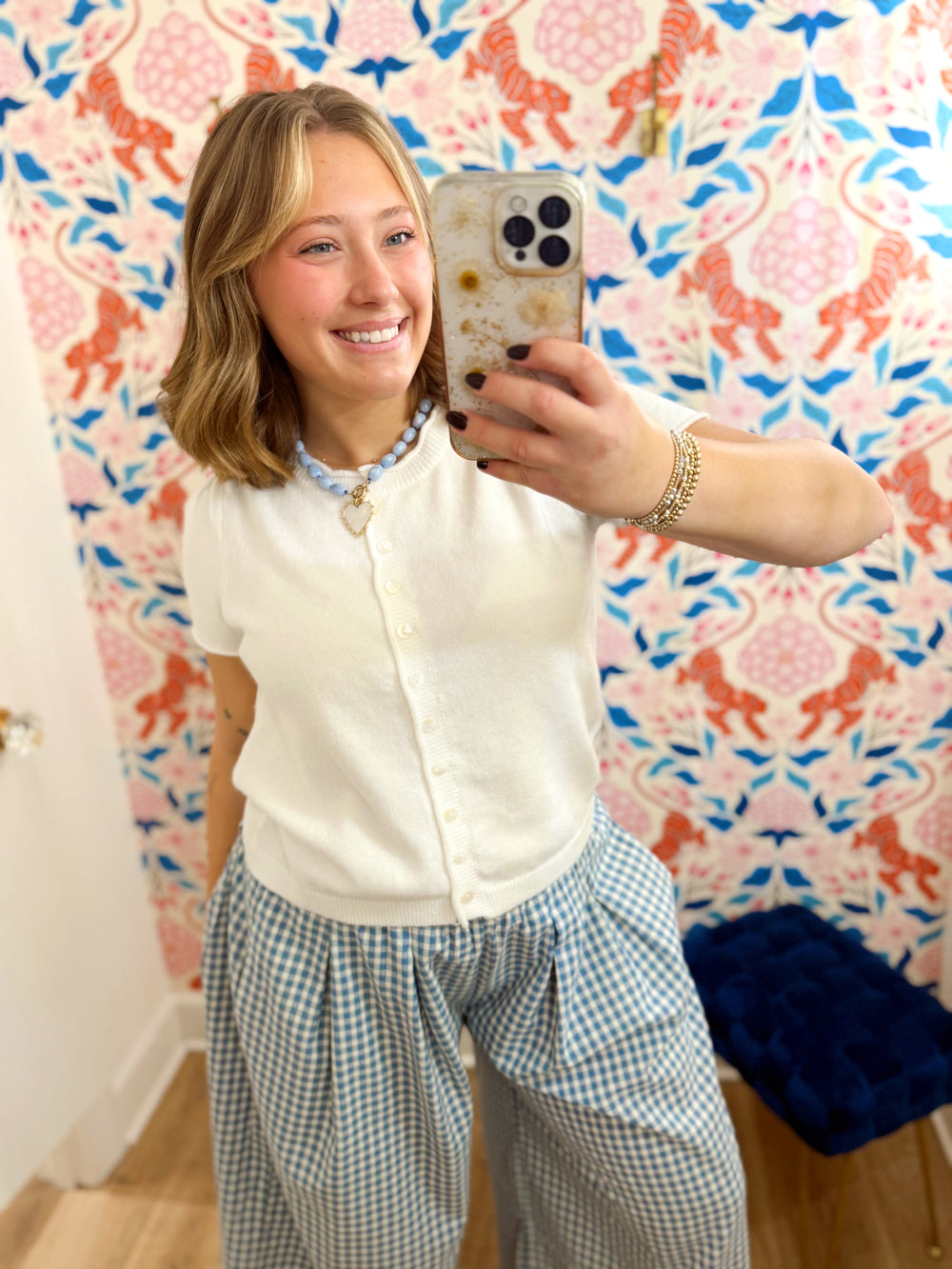 This cardigan features a classic cream color with a button-front design and feminine short sleeves.