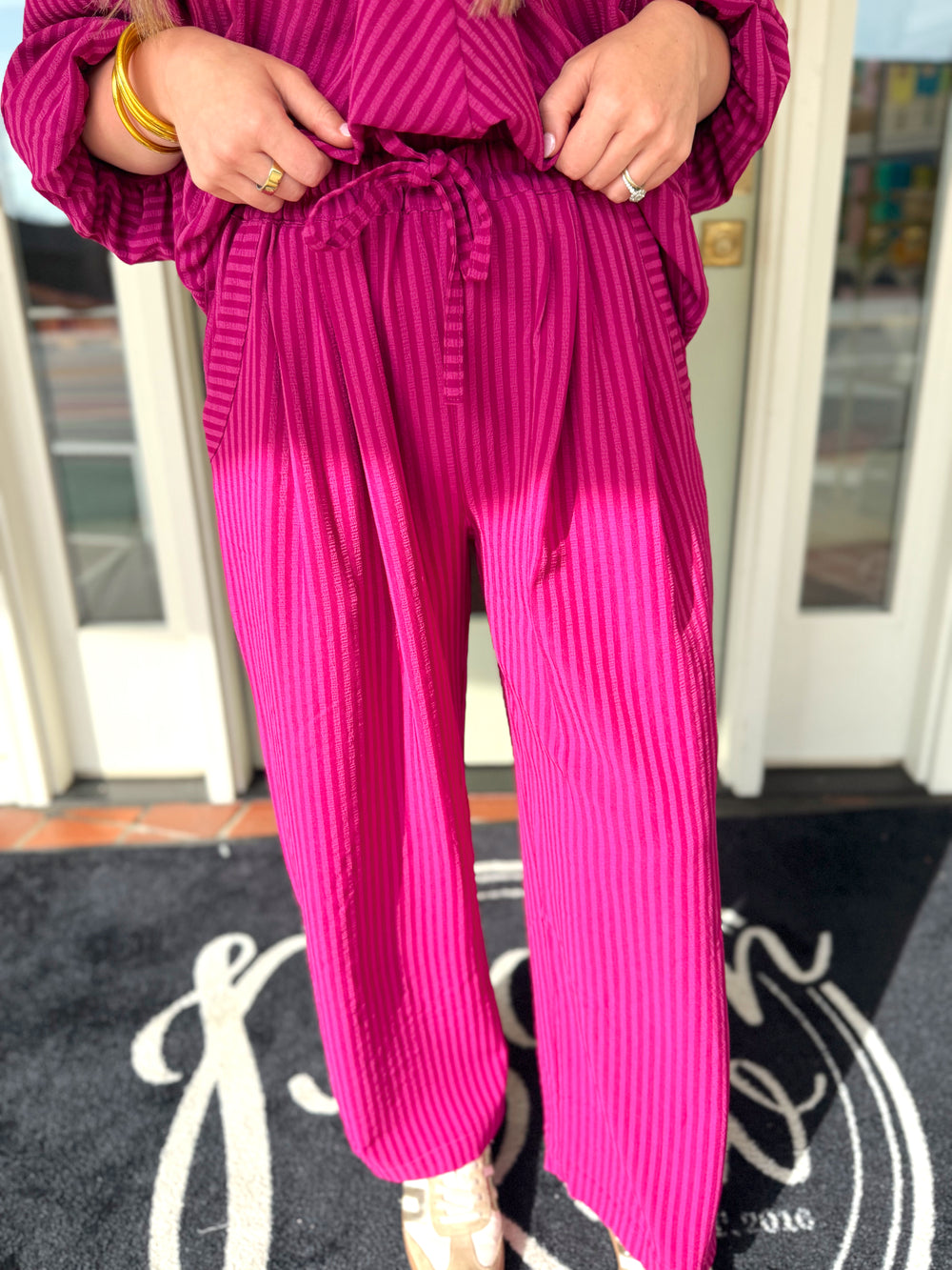 Magenta striped wide-leg pants with an elastic waist and drawstring.