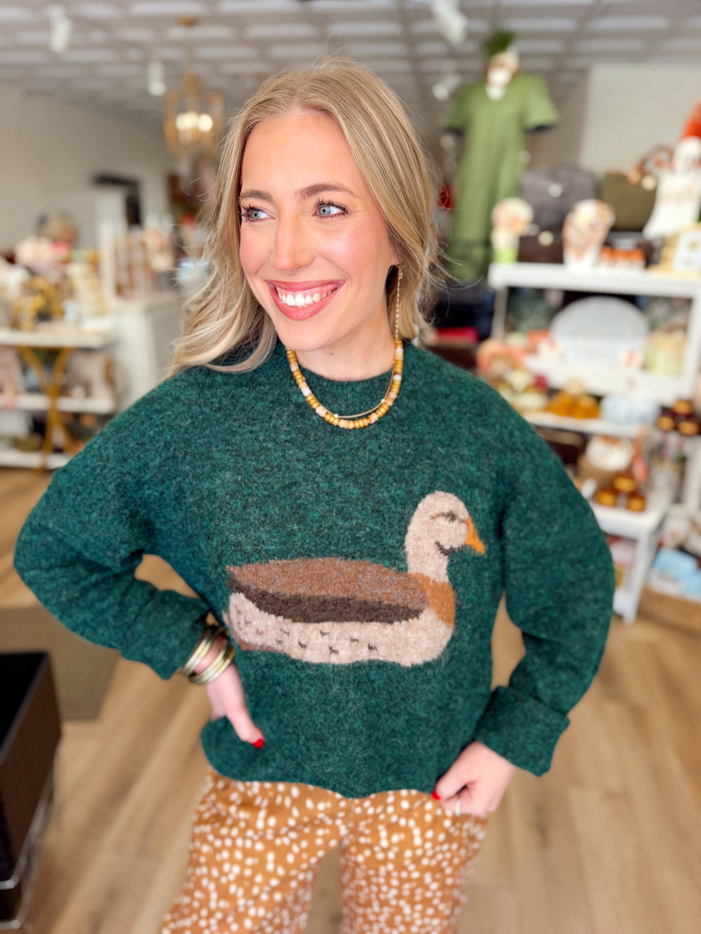 This cozy sweater features a beautifully detailed mallard duck design across the front in rich shades of forest green, brown, and cream.