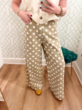 These pants feature an allover ivory polka dot print against a warm taupe background with a flattering high-rise fit and relaxed wide leg.