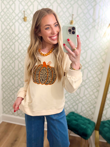 This cozy ivory sweatshirt features a statement leopard print pumpkin on the front for a fun twist on classic fall style.