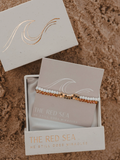 Bracelet set in a 'The Red Sea' box on a sandy background