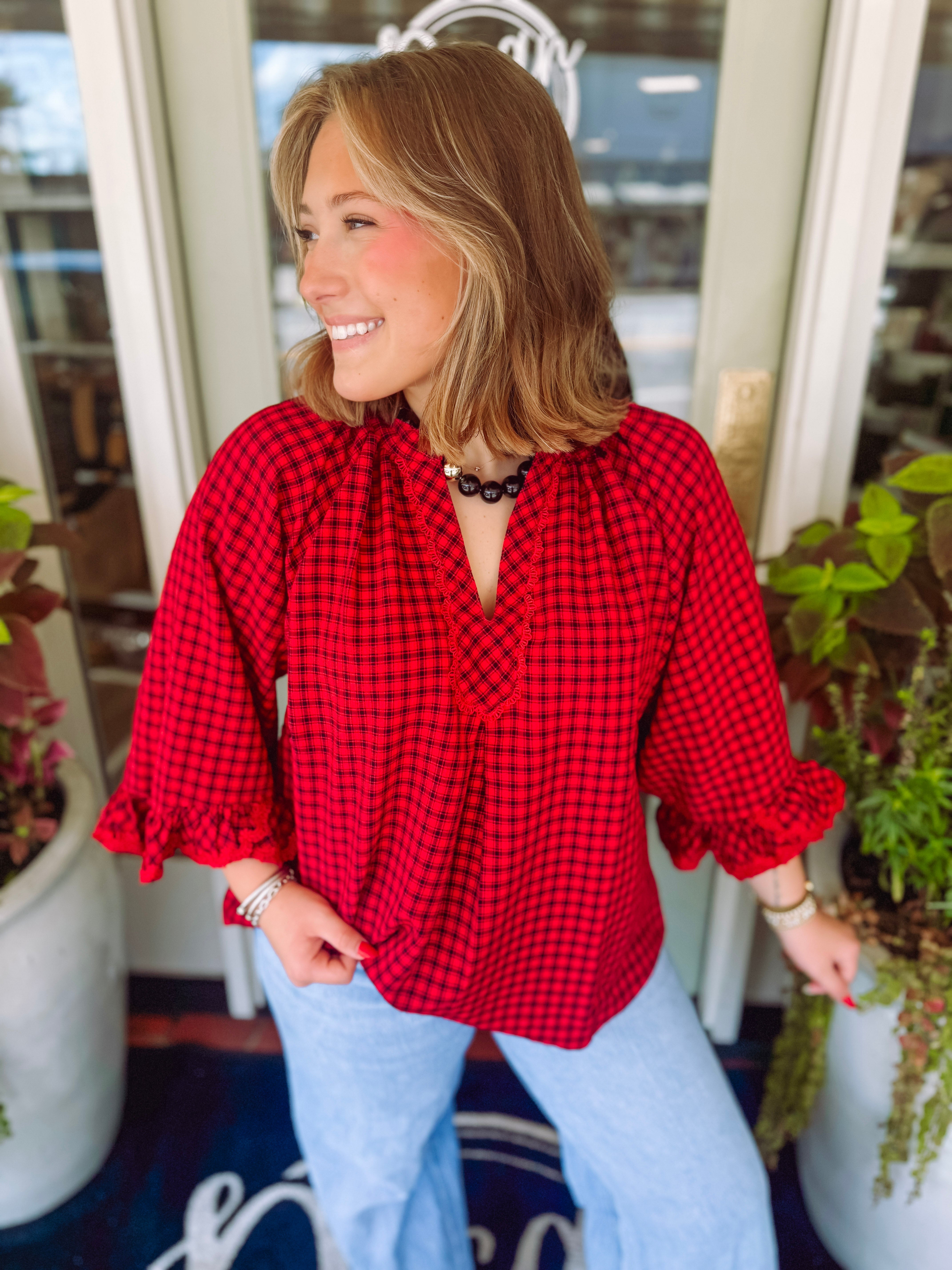 Red and black plaid v-neck top with a ruffle detail on the arms 