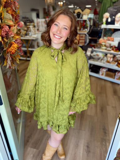 Textured semi-sheer mini dress featuring a self-tie bow neckline, long bell sleeves with layered ruffle cuffs, delicate lace trim details, and a double ruffle hem.