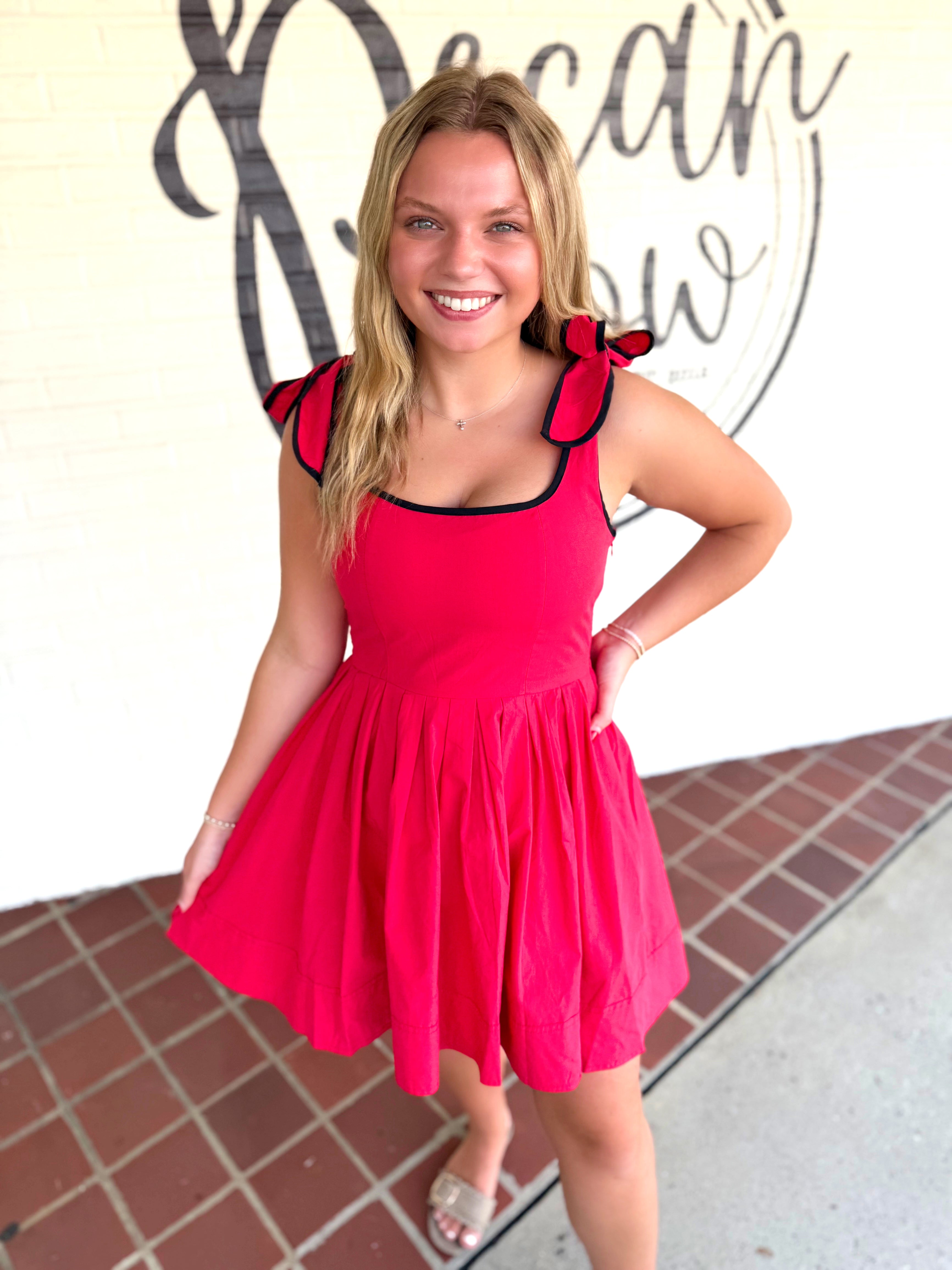 A red sleeveless dress with black trim and ruffled shoulder details