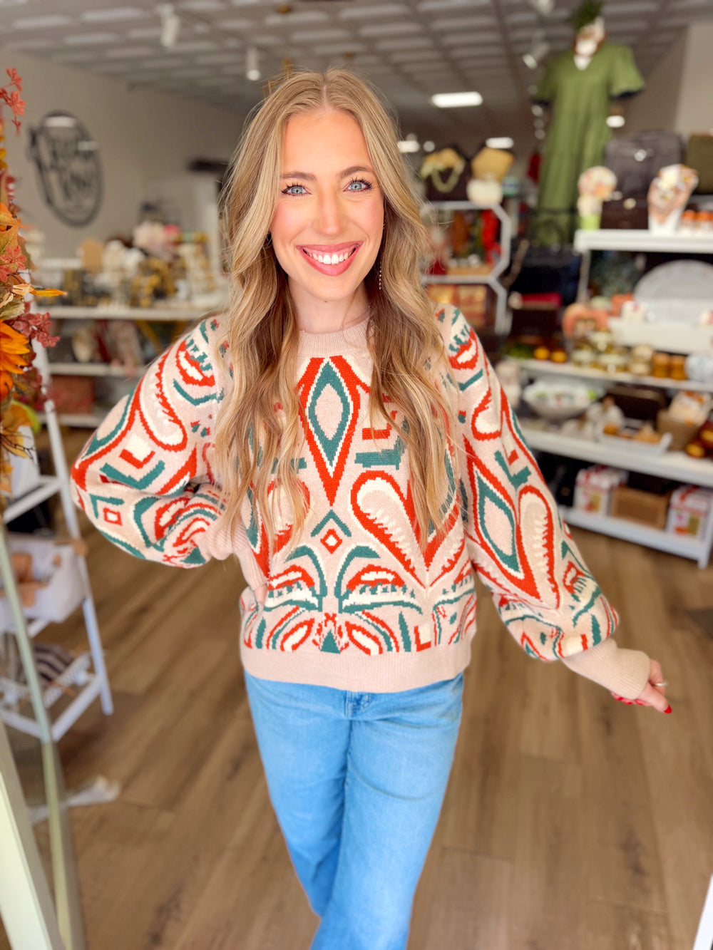 This cozy knit features an eye-catching abstract pattern in warm red and deep green against a soft oatmeal background.