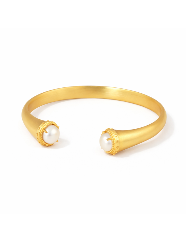 A gold open cuff bracelet featuring two textured gold end caps, each holding a round white pearl, set against a plain white background.