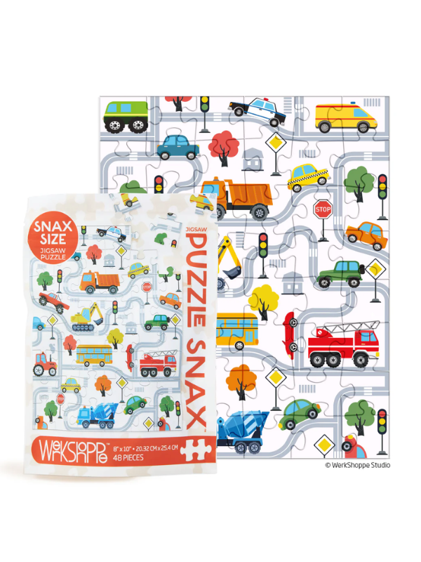 A children's jigsaw puzzle and its packaging featuring a colorful city street scene with cars, trucks, trees, and traffic lights. The package reads 'SNAK SIZE PUZZLE SNAX' and shows the brand 'Wasserpiper Studio'.