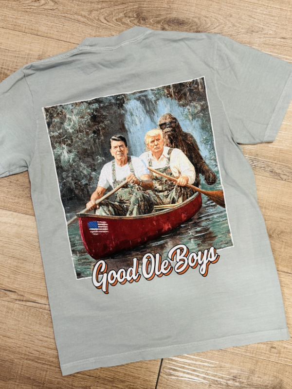 Gray t-shirt with a graphic of three men in a canoe and 'Good Ole Boys' text on a wooden surface.