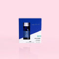 A boxed diffuser oil set on a pale pink background. The product packaging is blue and white, and a small dark glass diffuser bottle with a white cap is visible through a window on the front.