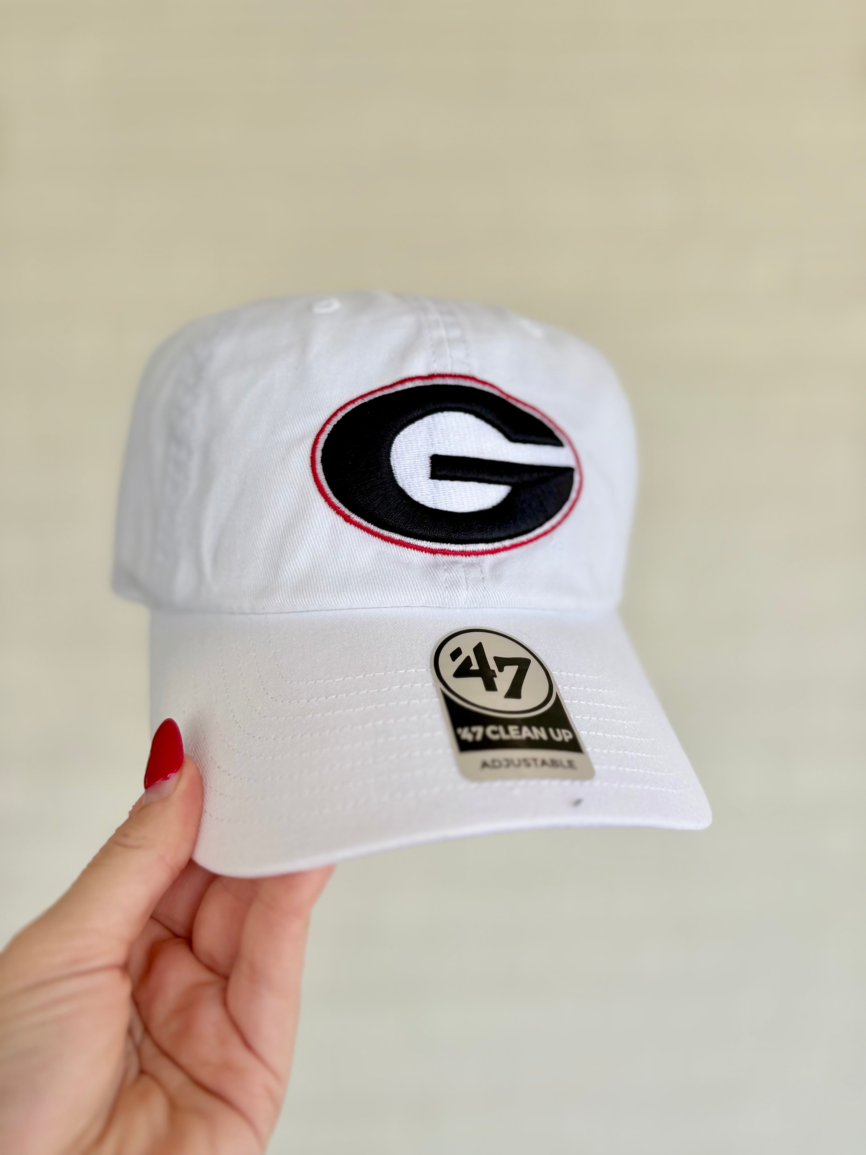 A white baseball cap featuring a Georgia Bulldogs logo on the front and a '47 Clean Fit sticker on the brim