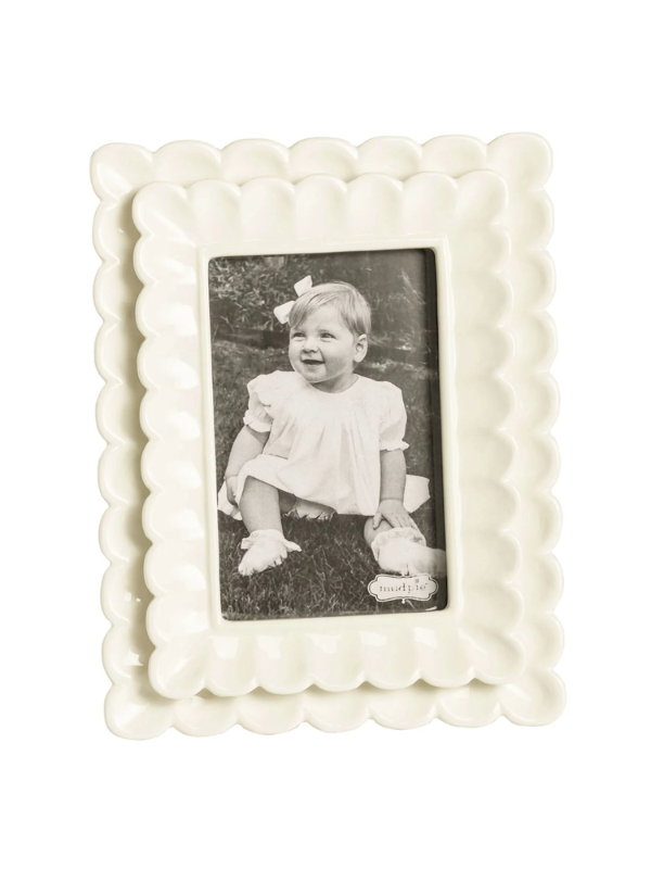 White decorative photo frame with a black and white photo of a child inside