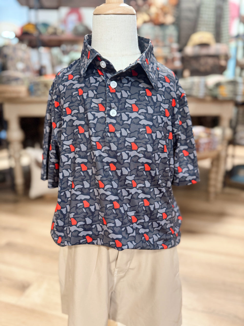 A polo that features gray and black camo-inspired print accented with pops of bold red, giving it the perfect Georgia-inspired color combination. 