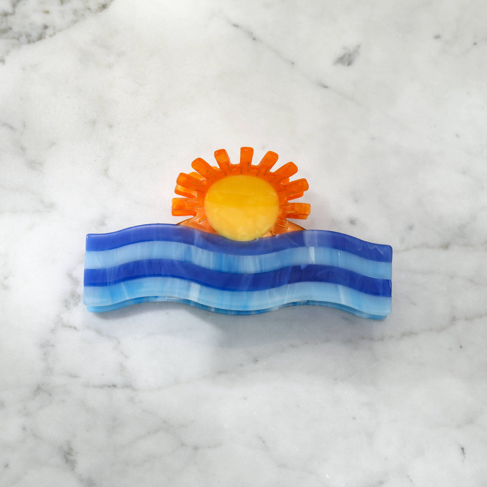 Decorative clip with a sun and wave design 