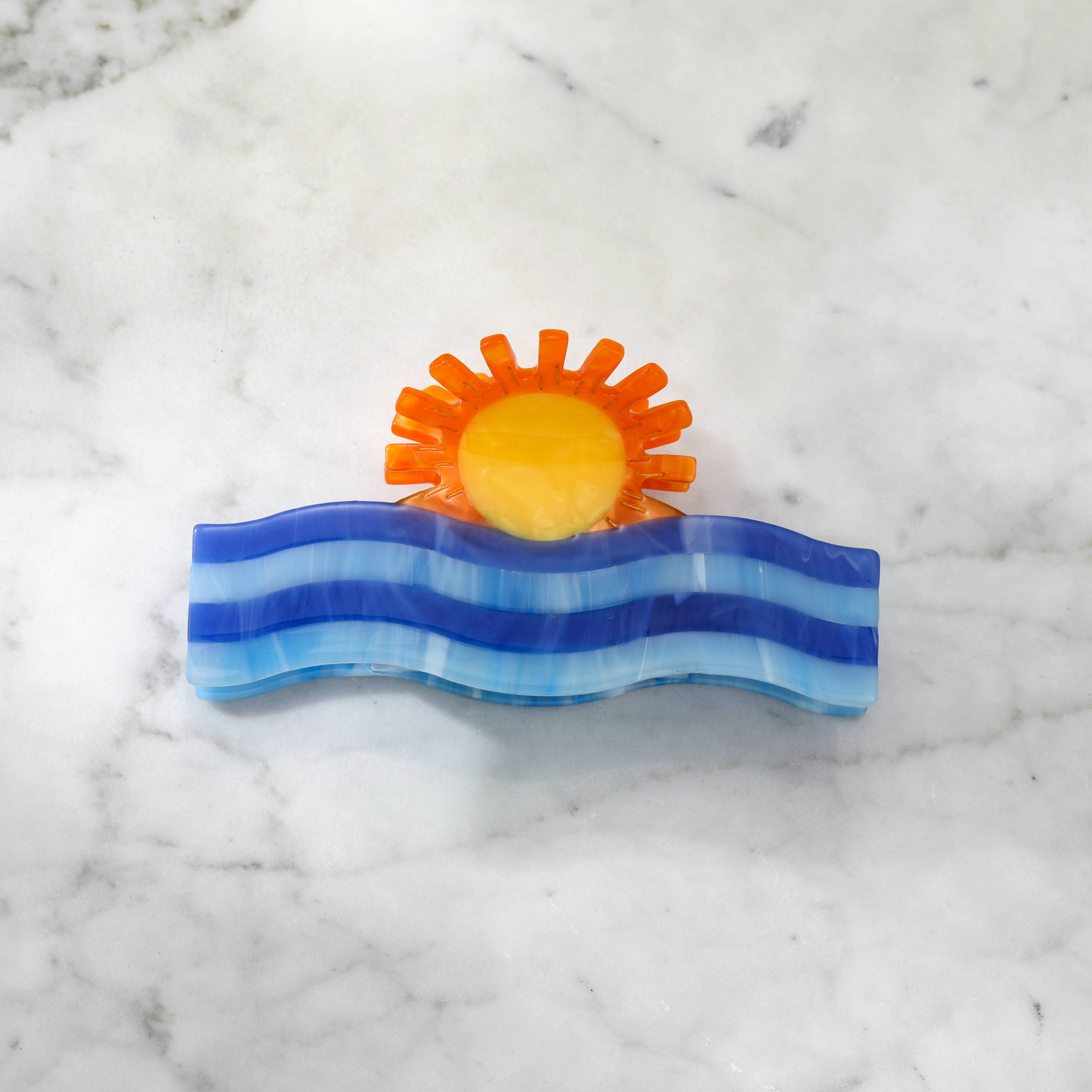 Decorative clip with a sun and wave design 