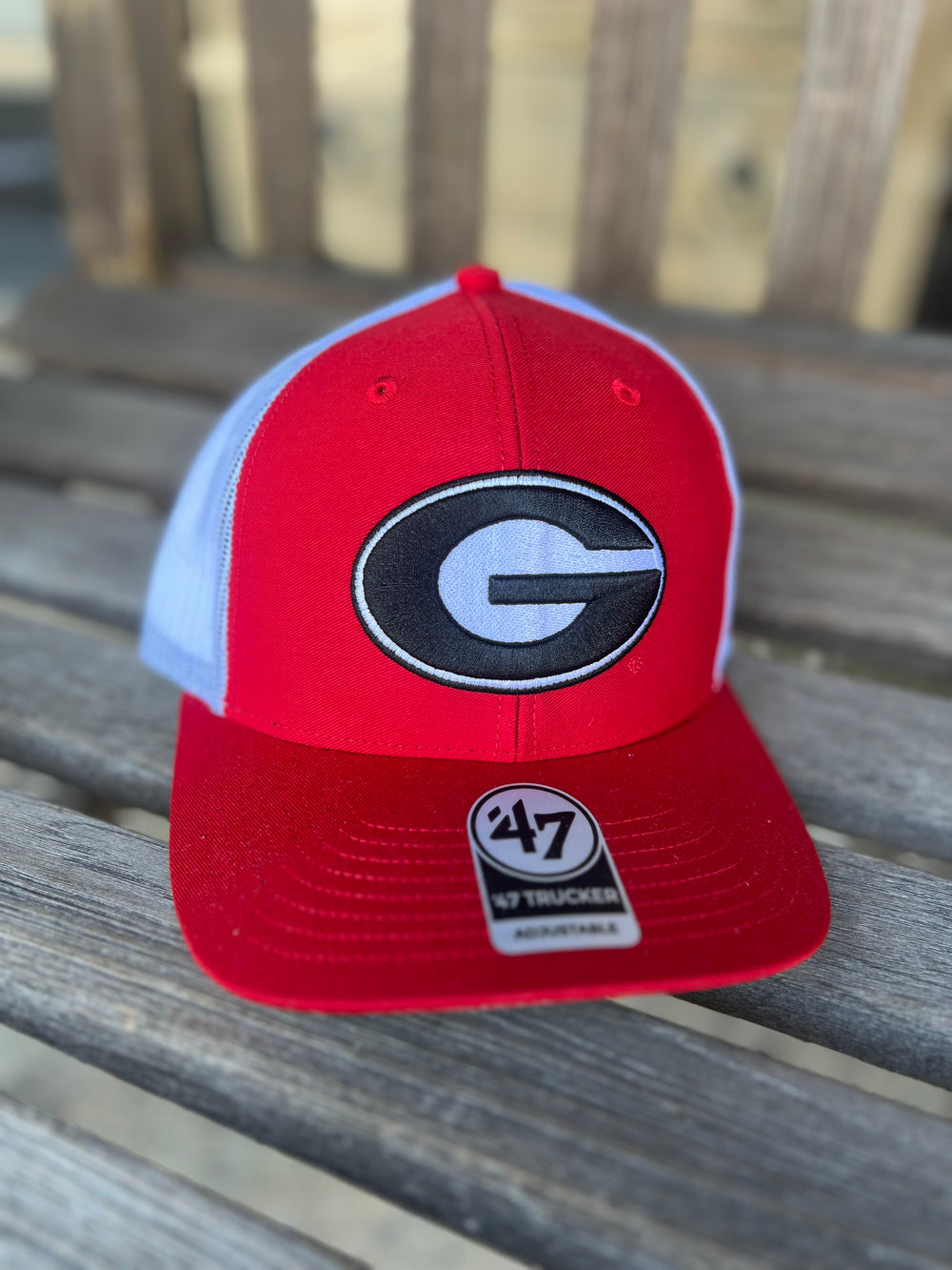A red and white trucker hat with the Georgia Bulldogs logo in the center, featuring a red bill and white mesh.