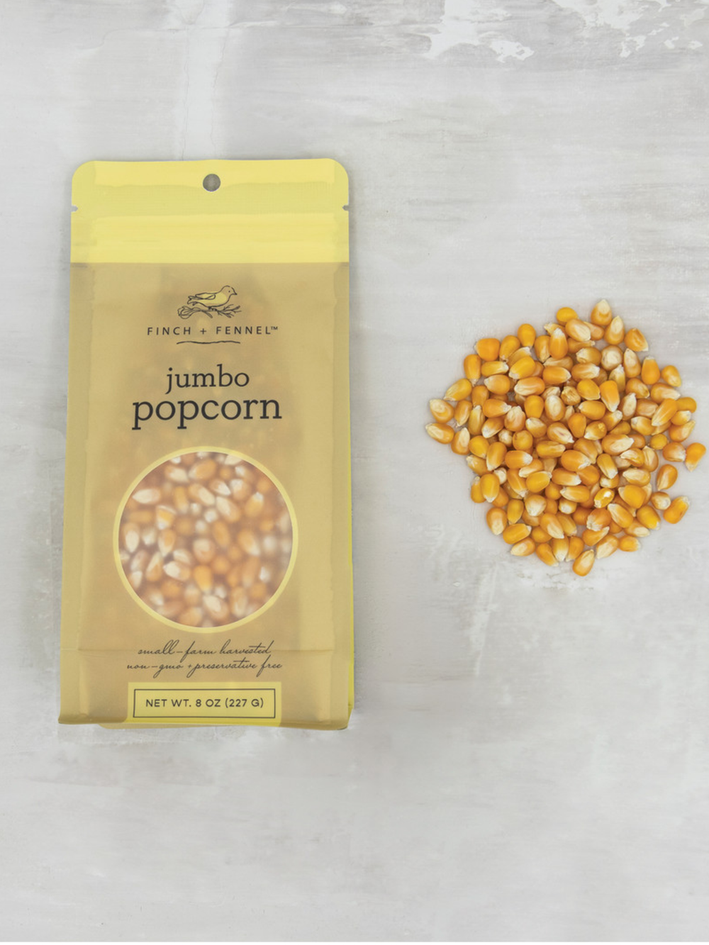Bag of Finch + Fennel Jumbo Popcorn Kernels with golden yellow popcorn kernels displayed beside the package, perfect for making large, fluffy homemade popcorn.