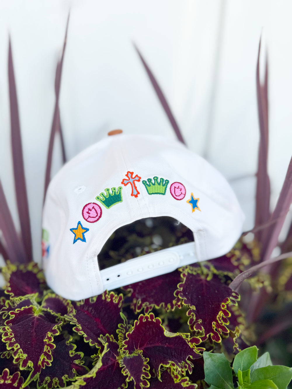 White trucker hat with colorful embroidered “Love Like Jesus” lettering, spotted tan brim, John 13:34 side embroidery, and colorful faith-inspired embroidered icons on the back.

