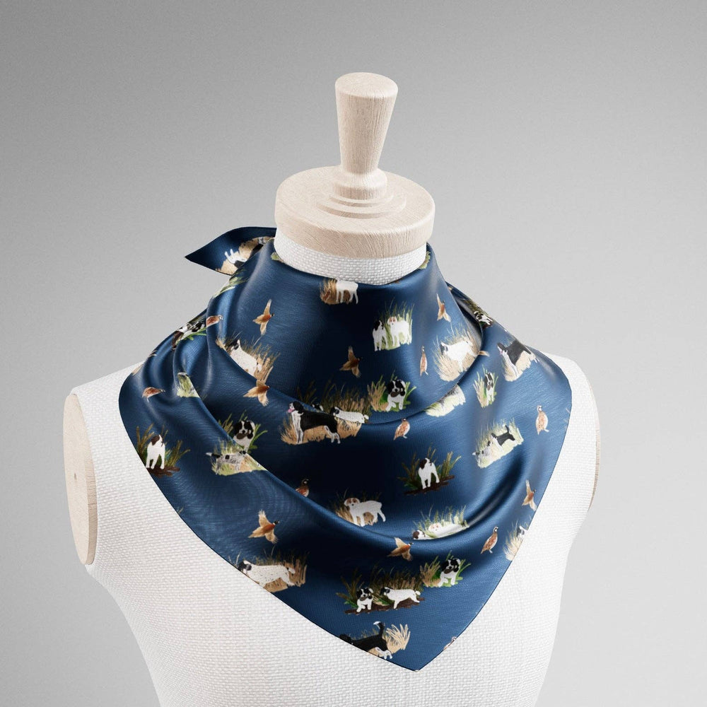 Navy satin neck scarf featuring an illustrated print of bird dogs, game birds, and grassy field scenes tied on a mannequin.